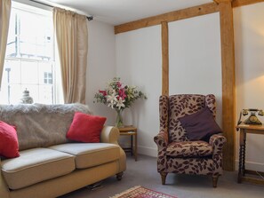 Un salon avec un canapé, un fauteuil et une petite table sur laquelle est posé un vase de fleurs.