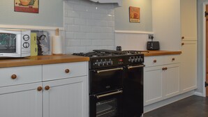 Une cuisine avec des meubles blancs, une cuisinière et un four à micro-ondes.