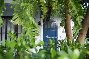 A building with a blue door marked "Welcome" and a number "105" on the wall.