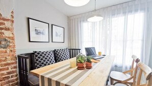 A modern dining area with a wooden table, striped cushions, and two potted plants. - Snoozy (Phuket)