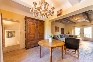 Un salón amplio con una mesa de comedor de madera, un sofá y una araña.