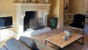 A cozy living room with a fireplace, comfortable seating, and a television. - Homerez - Villa in Saignon (Saignon)