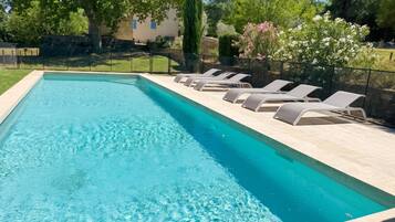 Une piscine rectangulaire à l’eau d’un bleu limpide, entourée d’une terrasse carrelée.