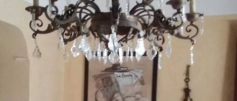 Ein Zimmer mit einer verzierten Schmiedeeisen-Konsole, einem gerahmten Kunstwerk, einer Chandelüster und einer Lampe.
