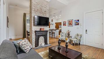 A living room with a fireplace, a television, and a dining area with chairs and a table.