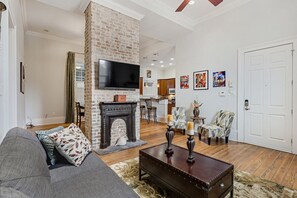 Una sala de estar con chimenea, televisión y comedor con sillas y mesa.