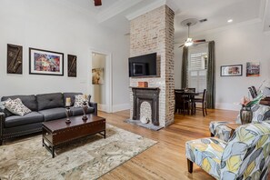 Una sala de estar con chimenea, un sofá, una mesa de centro y un televisor.