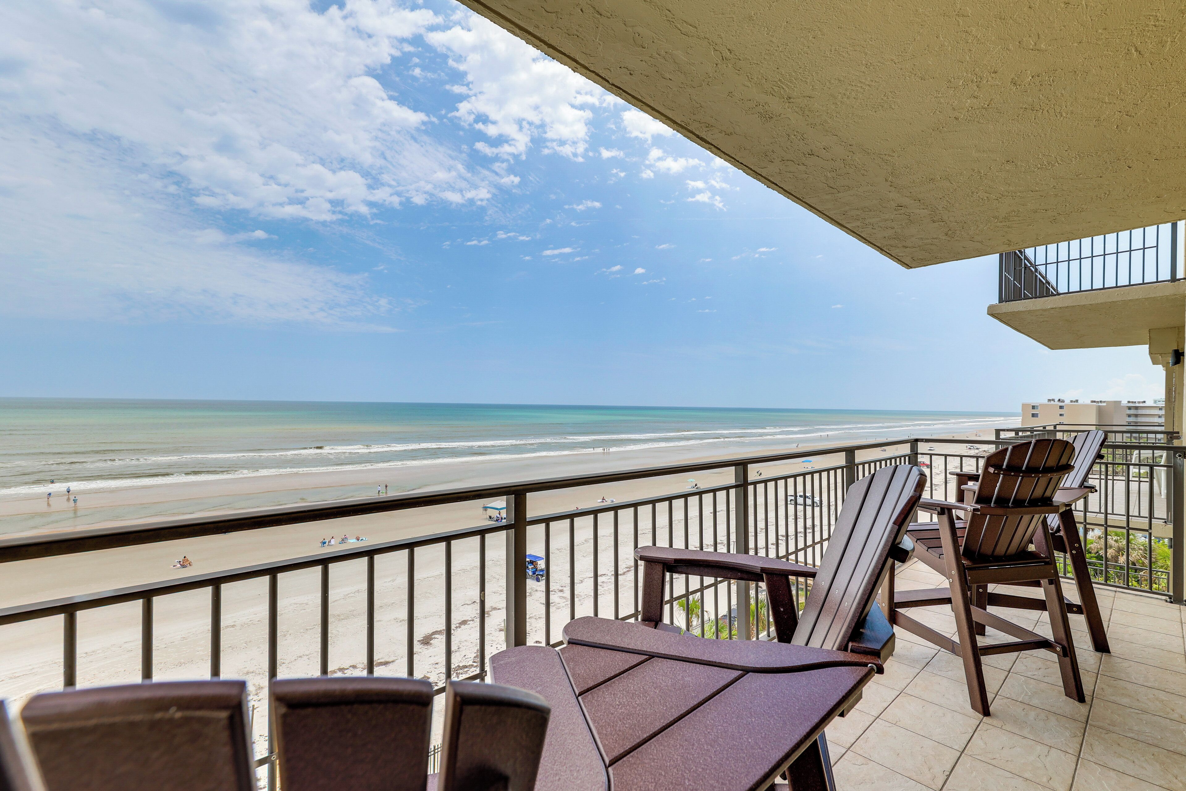 Un balcon donnant sur la plage, aménagé avec des chaises et une table en bois.