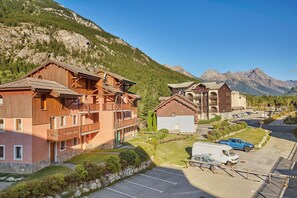 A mountain resort with wooden buildings, a parking area, and a view of the mountains.