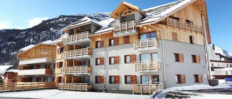 Un hôtel à plusieurs étages, doté de balcons en bois, avec une piste de ski en arrière-plan.