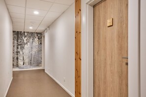 A hallway with a wooden door labeled '302' and a wall mural of a snowy forest.