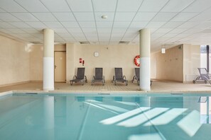 An indoor swimming pool with four lounge chairs, a fire alarm, and a clock on the wall. - Appart de Montagne Cosy | Service de Navette ! (Serre Chevalier)