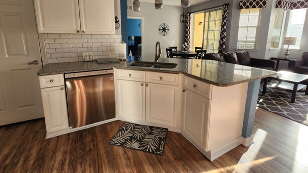 Una cocina moderna con armarios blancos, electrodomésticos de acero inoxidable y encimera de granito.