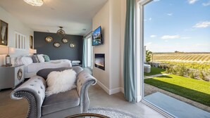 Ein modernes Schlafzimmer mit großem Fenster, Kamin und Blick auf einen Weinberg.