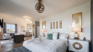 Ein modernes Schlafzimmer mit einem großen Bett, Nachttischen, einer Kronleuchter und Bildern an den Wänden.