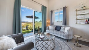 Ein Wohnzimmer mit grauem Sofa, einem runden Couchtisch und einer Glas-Stehlampe.