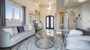 Ein geräumiges Wohnzimmer mit grauem Sofa, rundem Couchtisch und großem Fenster.