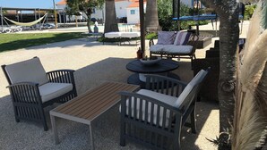 Un espace extérieur aménagé avec des meubles en osier, une table ronde et un hamac.