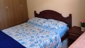 Ein Schlafzimmer mit einem Bett, einem Holzschrank und einem Nachttisch mit Blumen.