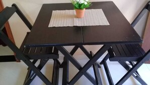 Ein quadratischer Tisch mit einer gewebten Tischmatte, umgeben von vier schwarzen Stühlen mit Kreuzgeflecht.