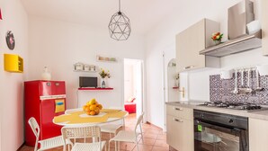 A compact kitchen with a red fridge, white chairs, a yellow table, and a black oven. - Edy Apartment (Palermo)