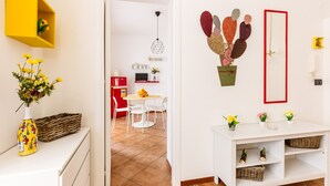 A modern living room with a white sofa, a small dining table, and a yellow shelf. - Edy Apartment (Palermo)