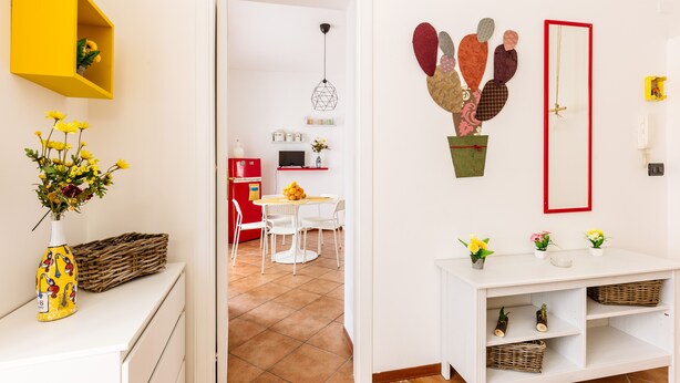 A modern living room with a white sofa, a small dining table, and a yellow shelf. - Edy Apartment (Palermo)