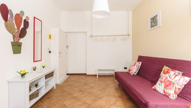 A living room with a red sofa, a white console table, and a hanging light fixture. - Edy Apartment (Palermo)