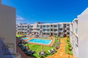 A hotel with multiple floors, a swimming pool, and outdoor seating areas.