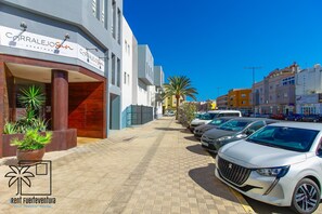 A parking lot with several cars, a building with a sign that reads 'CORRALEIDON,' and a clear blue sky.