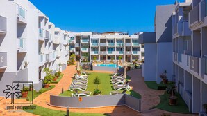A modern hotel with multiple floors, a central pool, and outdoor seating areas.