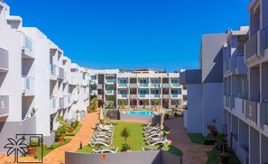 Um hotel moderno com vários andares, piscina central e áreas de estar ao ar livre.
