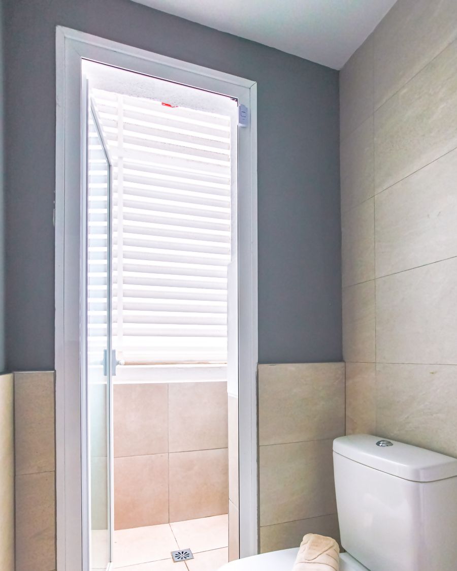 Un baño con inodoro, una toalla sobre el asiento y una puerta que da a un balcón.