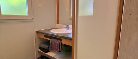Une salle de bain avec un lavabo, un miroir, un porte-serviettes et une fenêtre.
