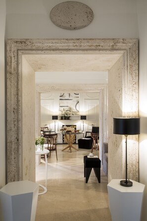 A spacious living area with a large mirror, a floor lamp, and a dining table with chairs.