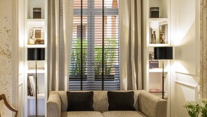A living room with a sofa, a coffee table, a bookshelf, and a window with blinds. - Residenza B (Rome)