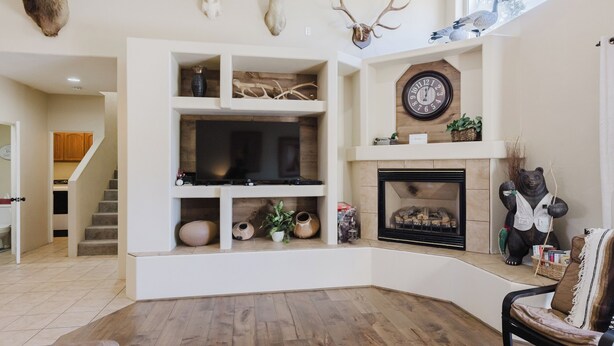 Un salon avec une cheminée, des têtes d’animaux empaillées accrochées au mur et une horloge.