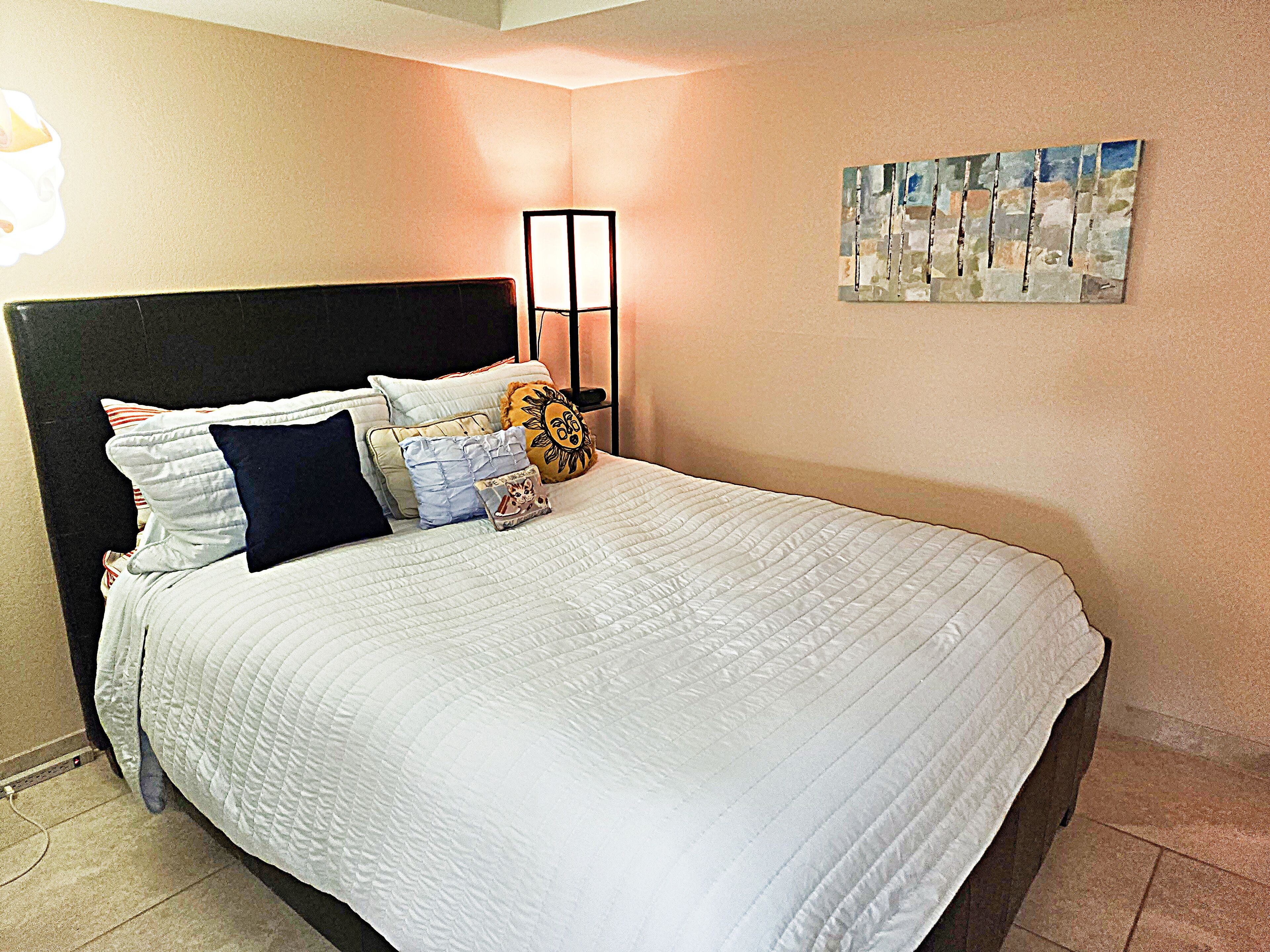 A neatly made bed with a white quilt, multiple pillows, and a headboard.