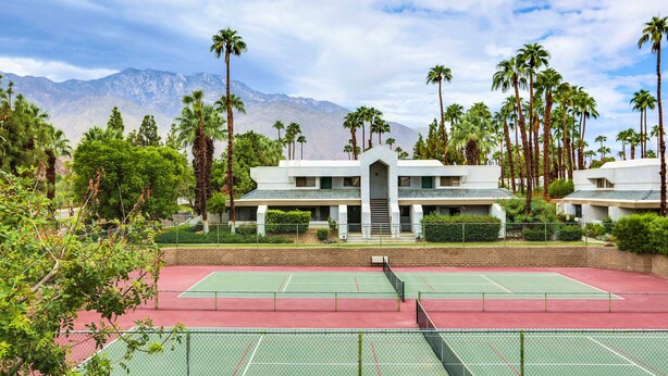 A tennis court with a building in the background. - South Palm Springs 2BR Condo. Affordable. Pool, Hot Tub, Golf, Hiking,
Tennis! (Palm Springs)
