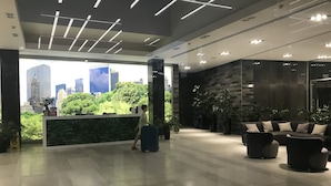 Un moderno vestíbulo con mostrador de recepción, zona de estar y vistas a la ciudad.