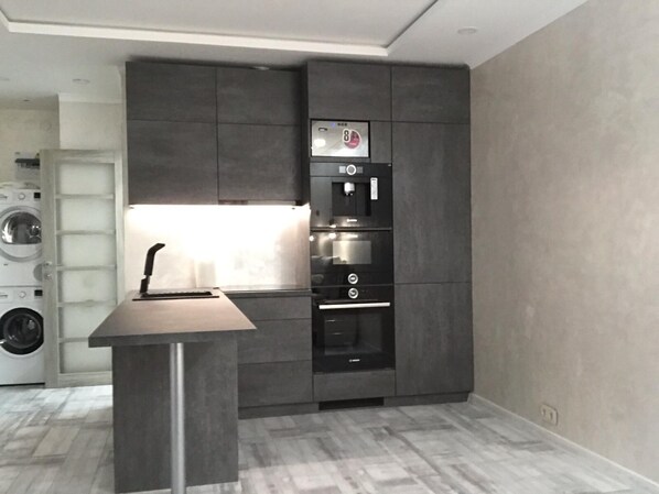 Una cocina moderna con electrodomésticos integrados, una isla central y una lavadora al fondo.