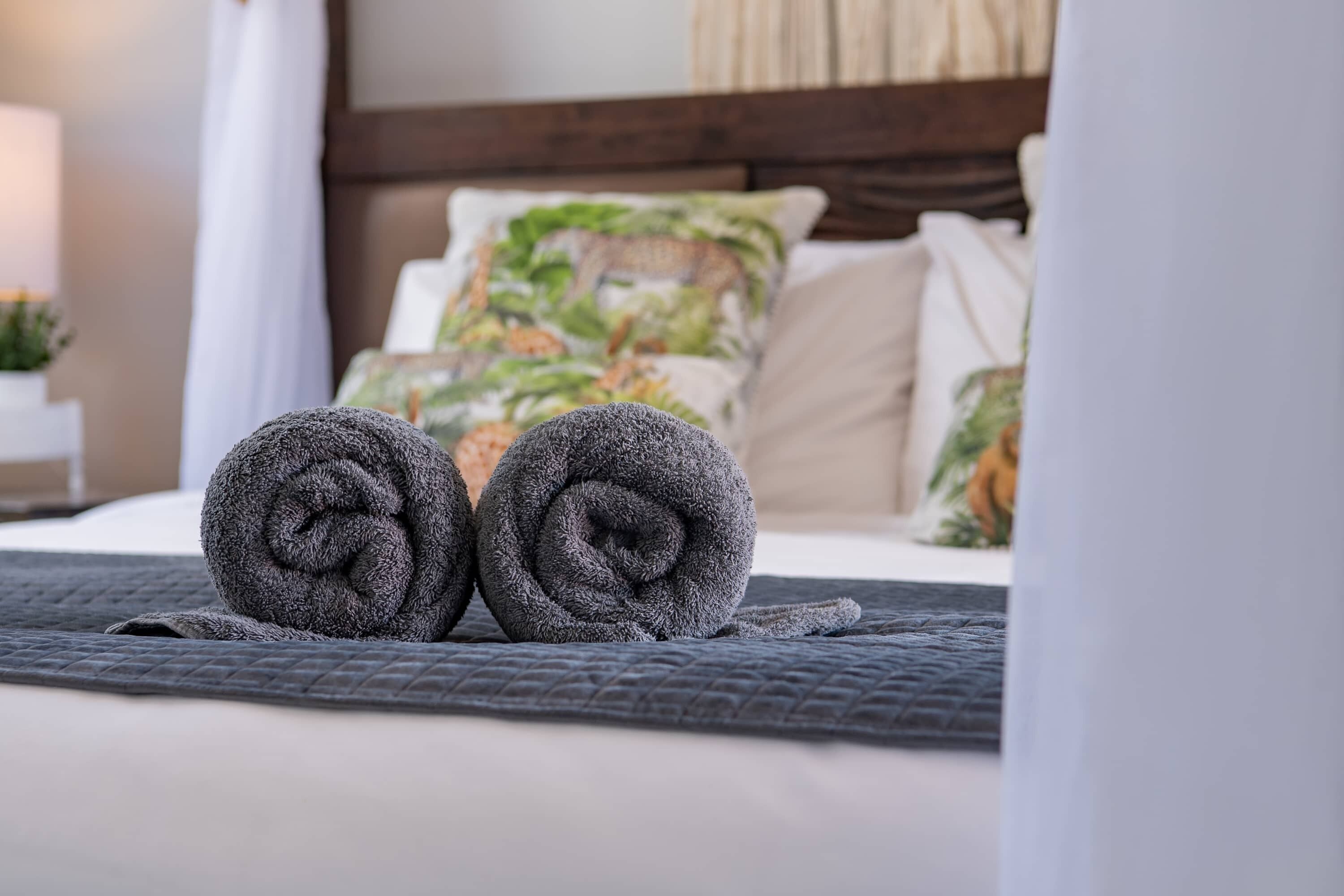 Un lit bien fait, avec des serviettes enroulées et une couverture matelassée.