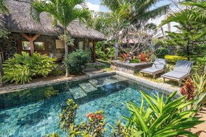 A pool surrounded by lush greenery and a thatched-roof structure. - LUXURY PARADIS VILLA ***** (Pereybere)