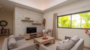 A modern living room with a flat-screen TV, two sofas, a coffee table, and a fireplace.