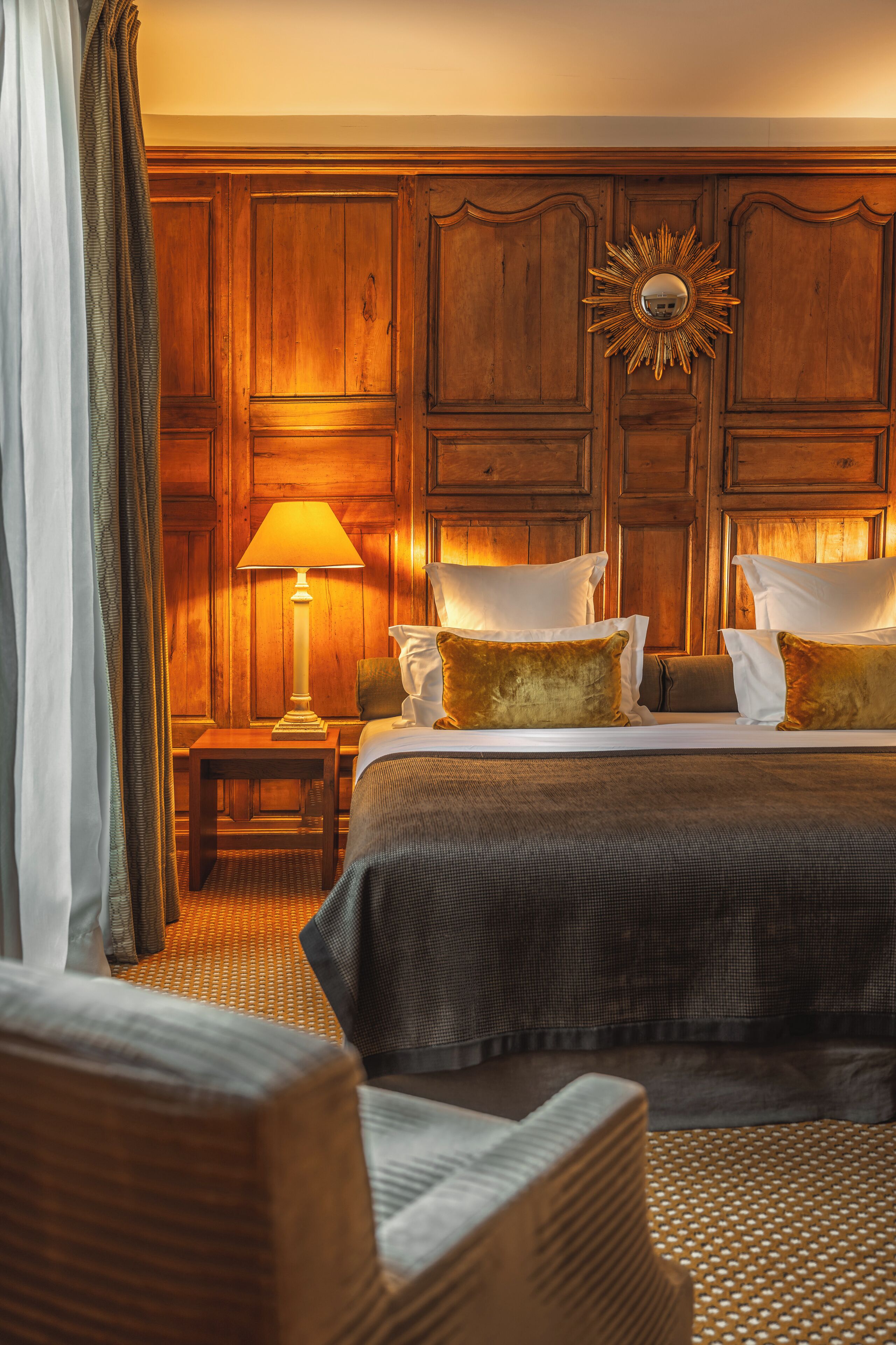Ein Hotelzimmer mit einem großen Bett, einem Nachttisch, einer Lampe und einem Spiegel.