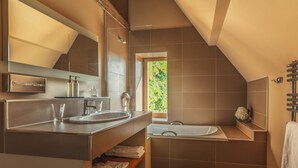 A modern bathroom with a large mirror, a sink, and a bathtub.