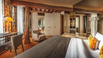Habitación de hotel con cama, escritorio, silla, espejo y vista al baño.