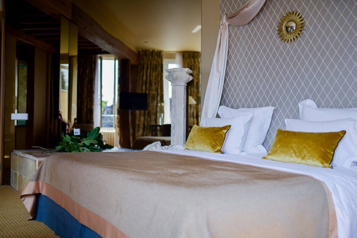 Une chambre d’hôtel dotée d’un grand lit, d’un baldaquin, d’un mur décoratif et offrant une vue sur l’extérieur.