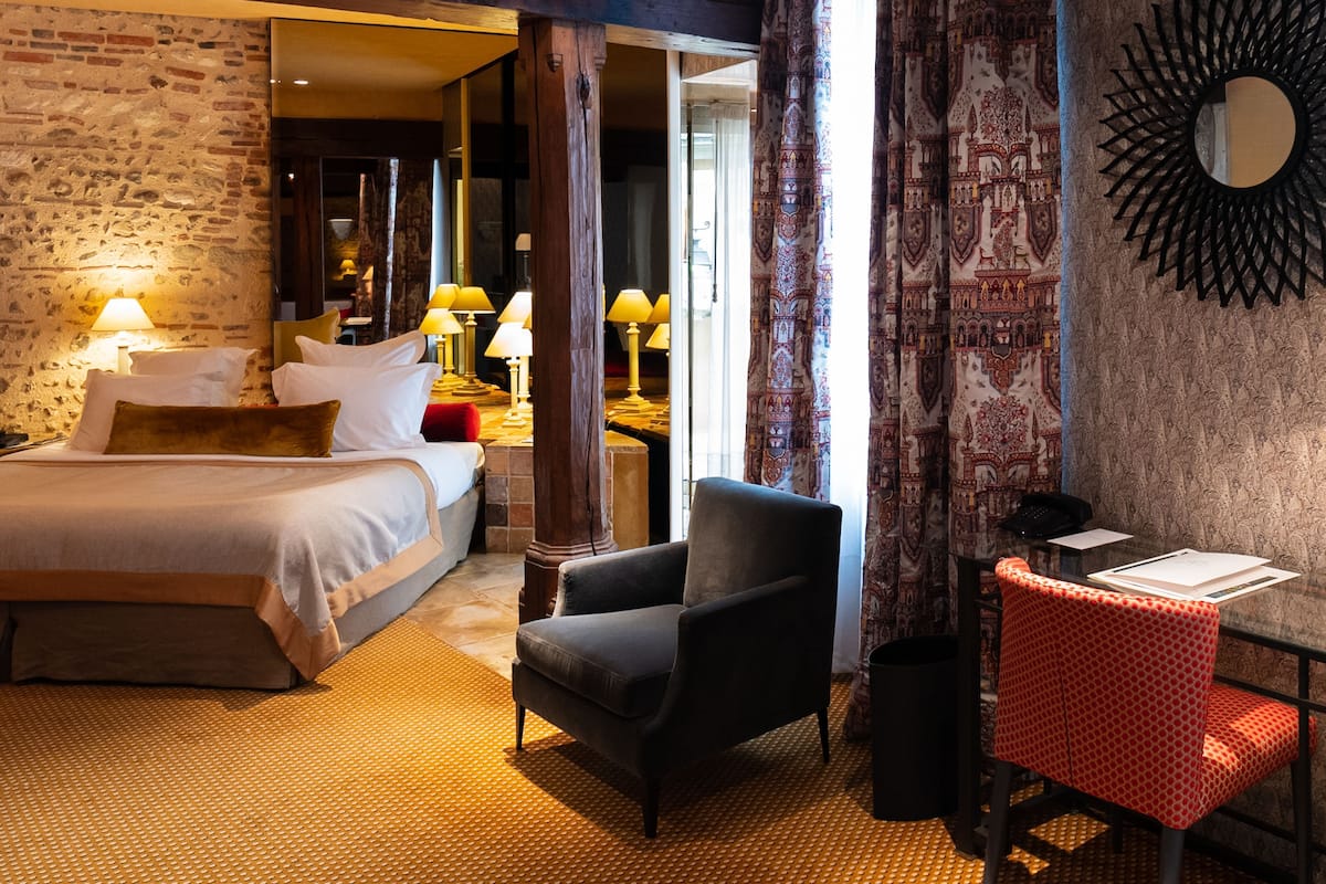 Une chambre d’hôtel avec un lit, une chaise, un bureau avec une chaise et un mur décoré d’un motif.