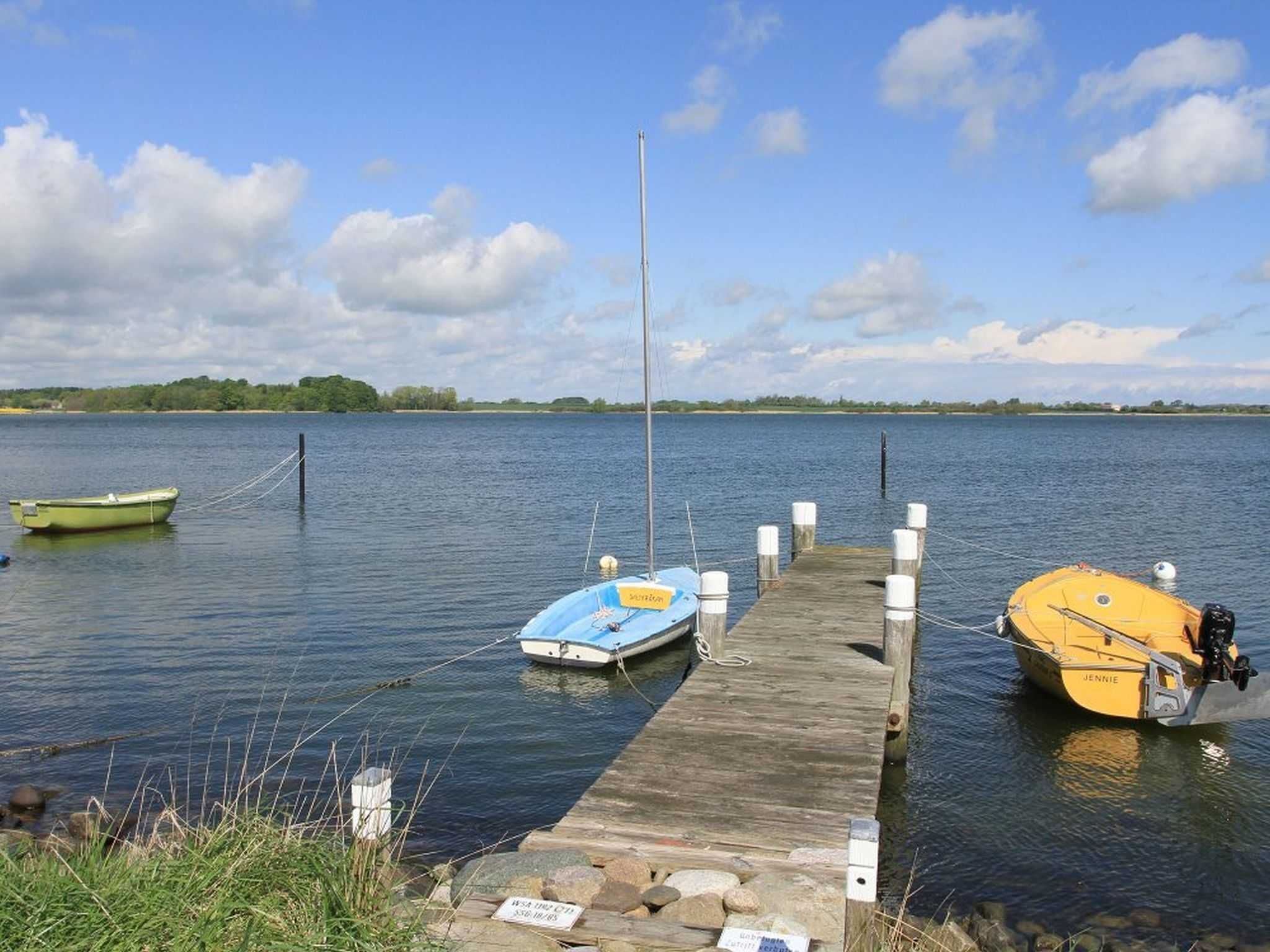 A wooden dock with two boats moored at the end.